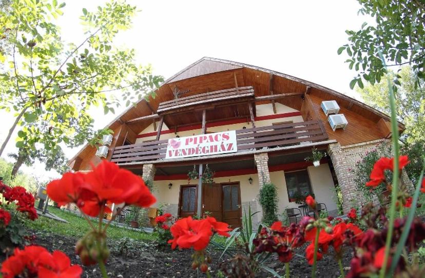 ein Gebäude mit roten Blumen davor in der Unterkunft Pipacs Vendégház in Poroszló