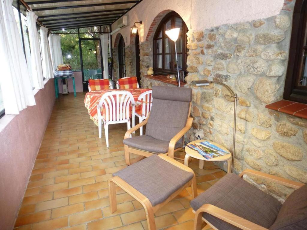 a patio with chairs and a table and a stone wall at Maisonette rustique- pinède piscine in Argelès-sur-Mer