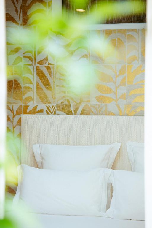 a bed with white pillows in front of a wall at Boutique Hôtel Villa Fabulite in Antibes