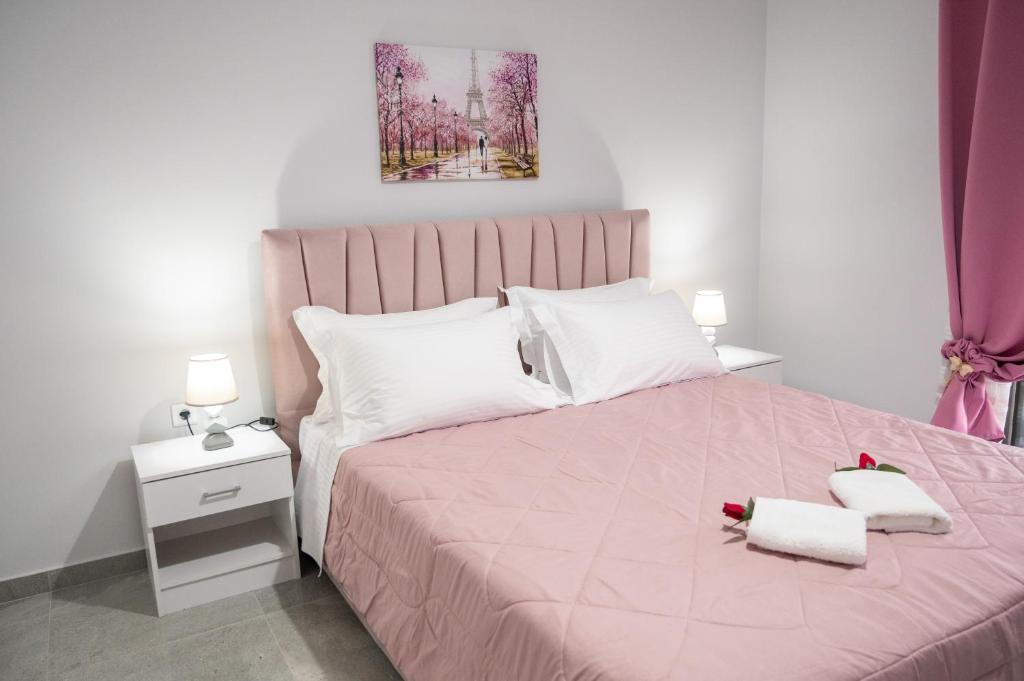 um quarto com uma cama rosa com duas toalhas em 3S Tolo Apartments em Tolo