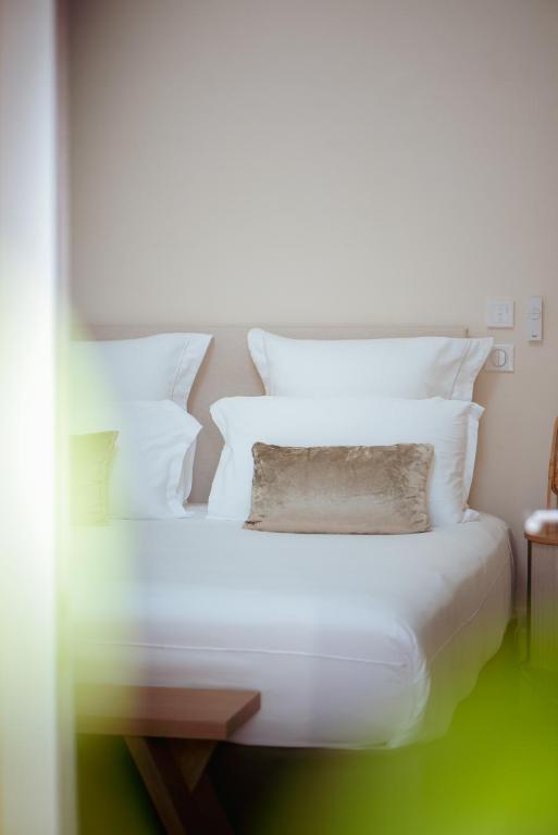 a bed with white sheets and pillows in a room at Boutique Hôtel Villa Fabulite in Antibes