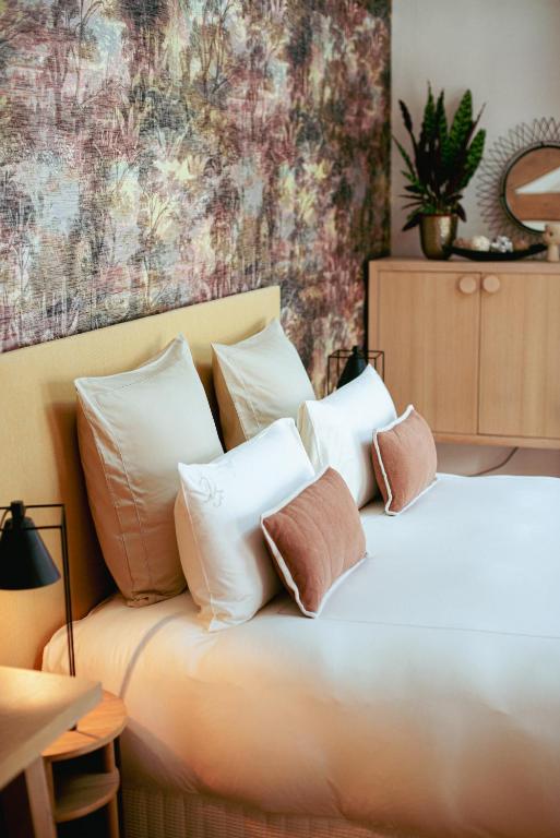 a bed with white pillows and a painting on the wall at Boutique Hôtel Villa Fabulite in Antibes