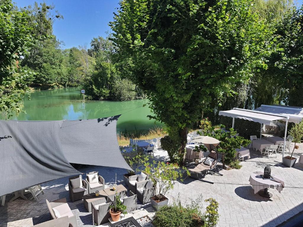 a pool of water with tables and chairs next to a lake at LOGIS - Hôtel & Restaurant Le Gonfalon in Germigny-lʼEvêque