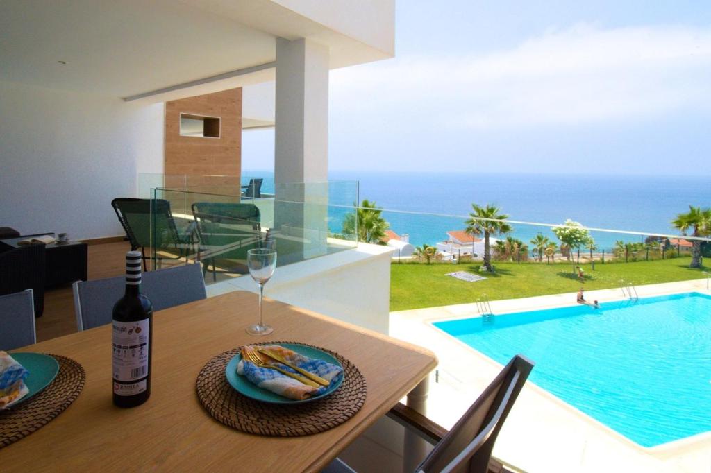 a dining table with a bottle of wine next to a swimming pool at THE SEA VIEW CALACEITE in Torrox Costa
