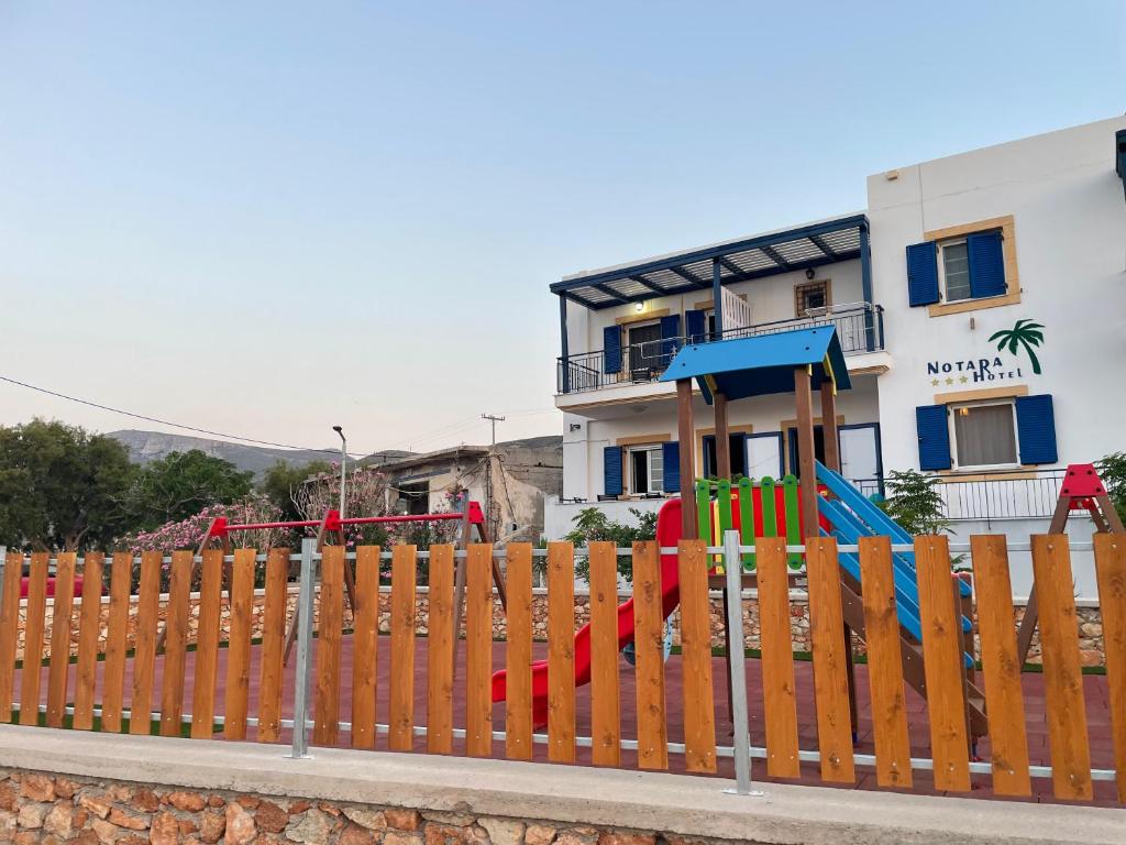 a wooden fence with a playground in front of a building at Diakofti house by the sea - Kythoikies hoilday houses in Kythira