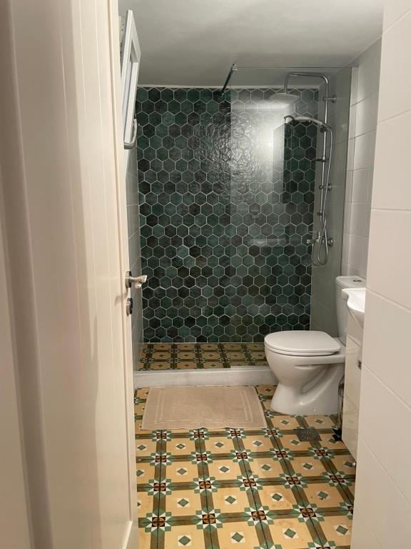 a bathroom with a shower and a toilet with a tile floor at Diakofti house by the sea - Kythoikies hoilday houses in Kythira