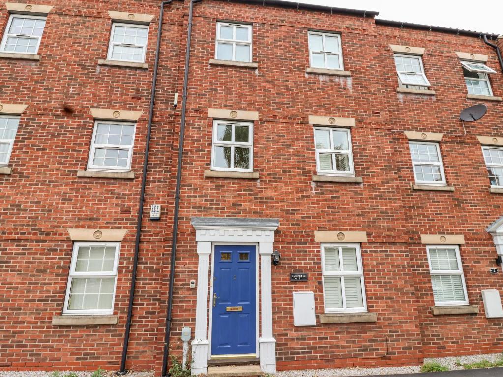 um edifício de tijolos vermelhos com uma porta azul em 1 Cockerill Fold em Beverley