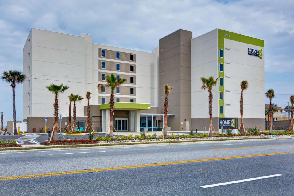 uma estrada vazia em frente a um hotel com palmeiras em Home2 Suites Ormond Beach Oceanfront, FL em Ormond Beach