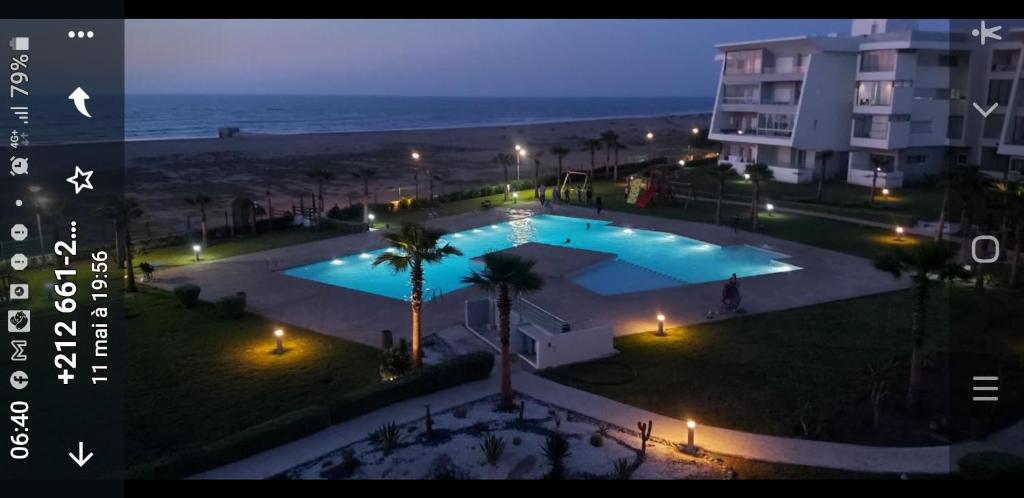 a view of a swimming pool at night with the beach at Luxueux appartement front mer in Sidi Rahal