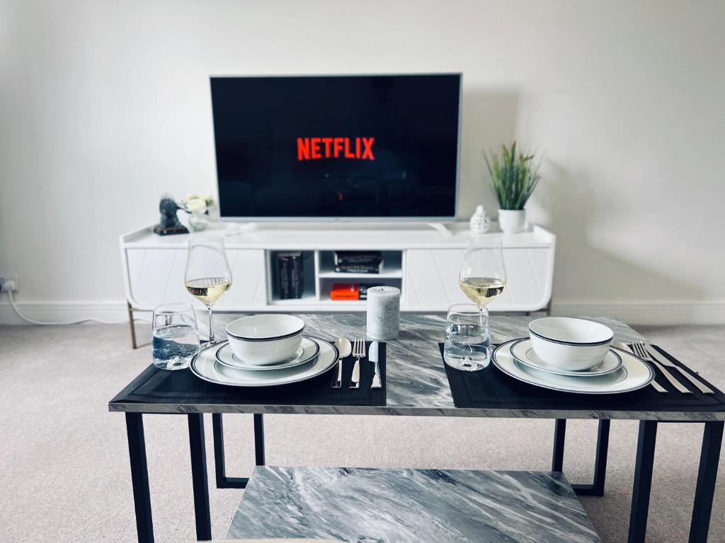 a table with two glasses of wine and a tv at Deluxe 2 Bedroom Apartment in Sheffield