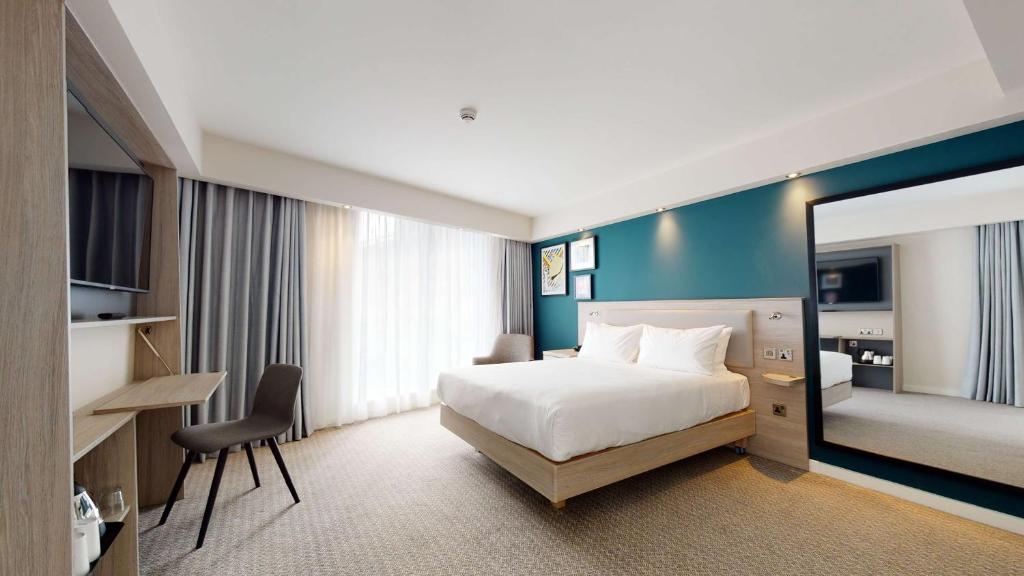 マンチェスターにあるHampton By Hilton Manchester Northern Quarterのベッドと大きな鏡が備わるホテルルームです。