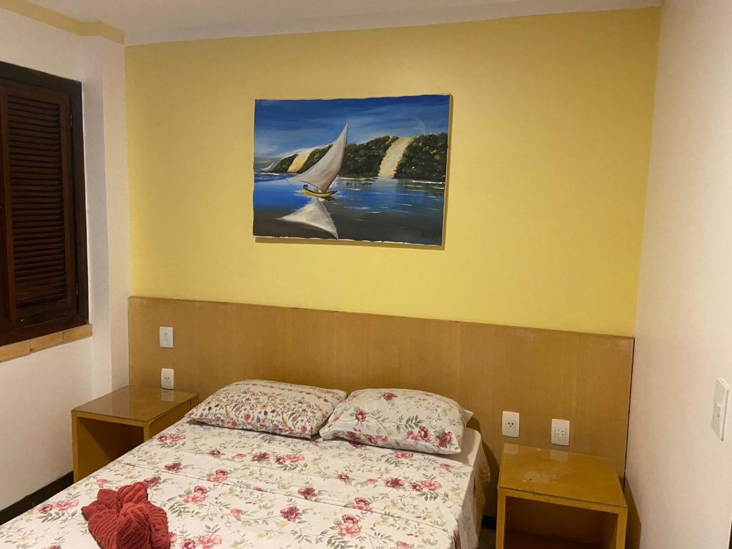 um quarto com uma cama e um quadro na parede em Apartamentos Ponta do Sol em Natal