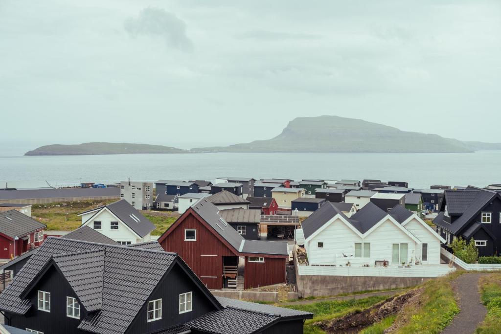 a village with houses and the ocean in the background at New Three Bedroom Townhouses with Sea View in Tórshavn