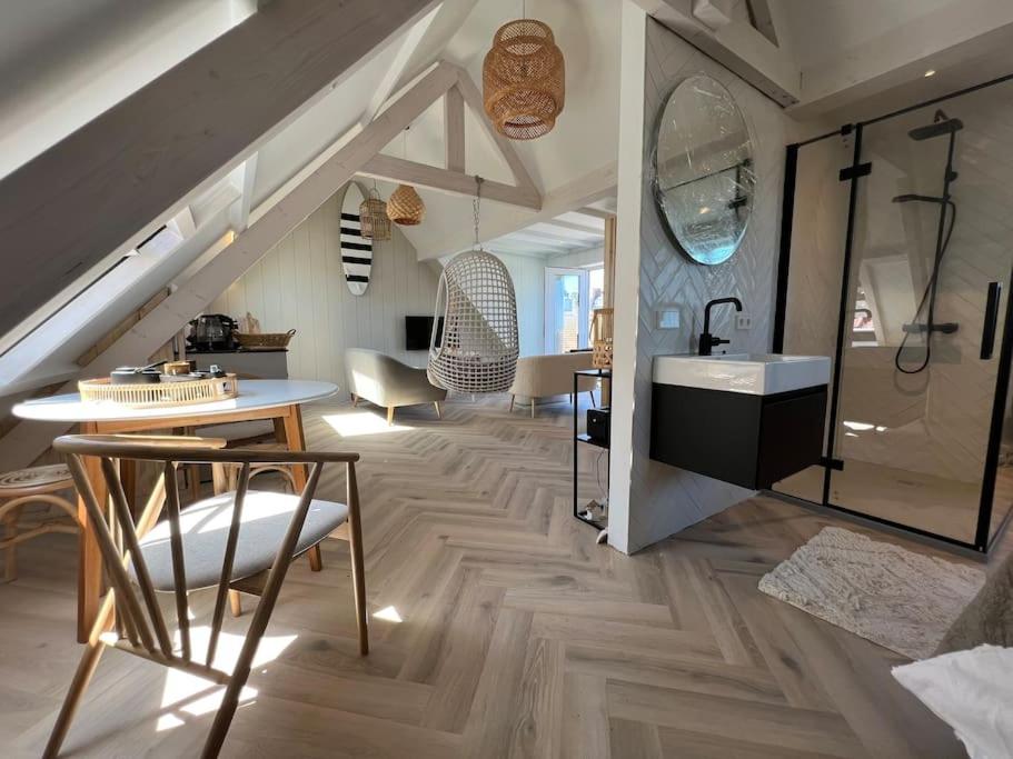 a bathroom with a sink and a table in a room at Loft met zeezicht in Egmond aan Zee