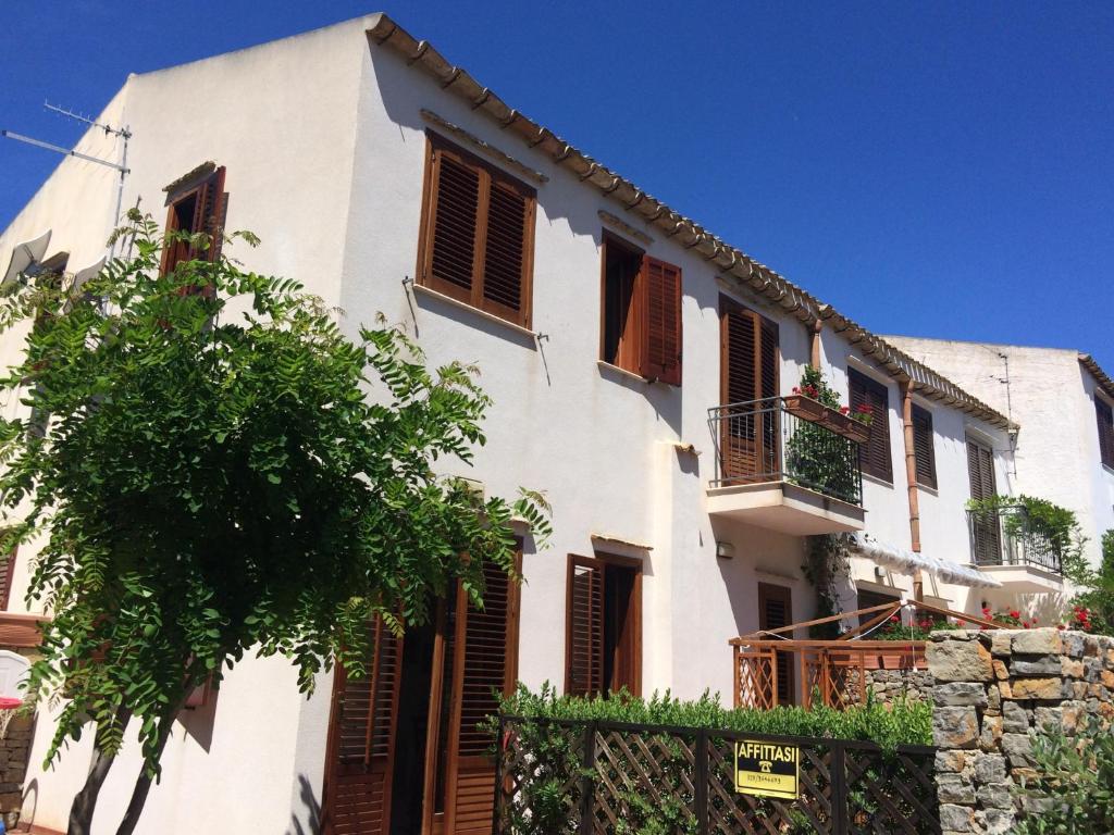 a white house with brown shuttered windows and a tree at Villa Giuliana in San Vito lo Capo