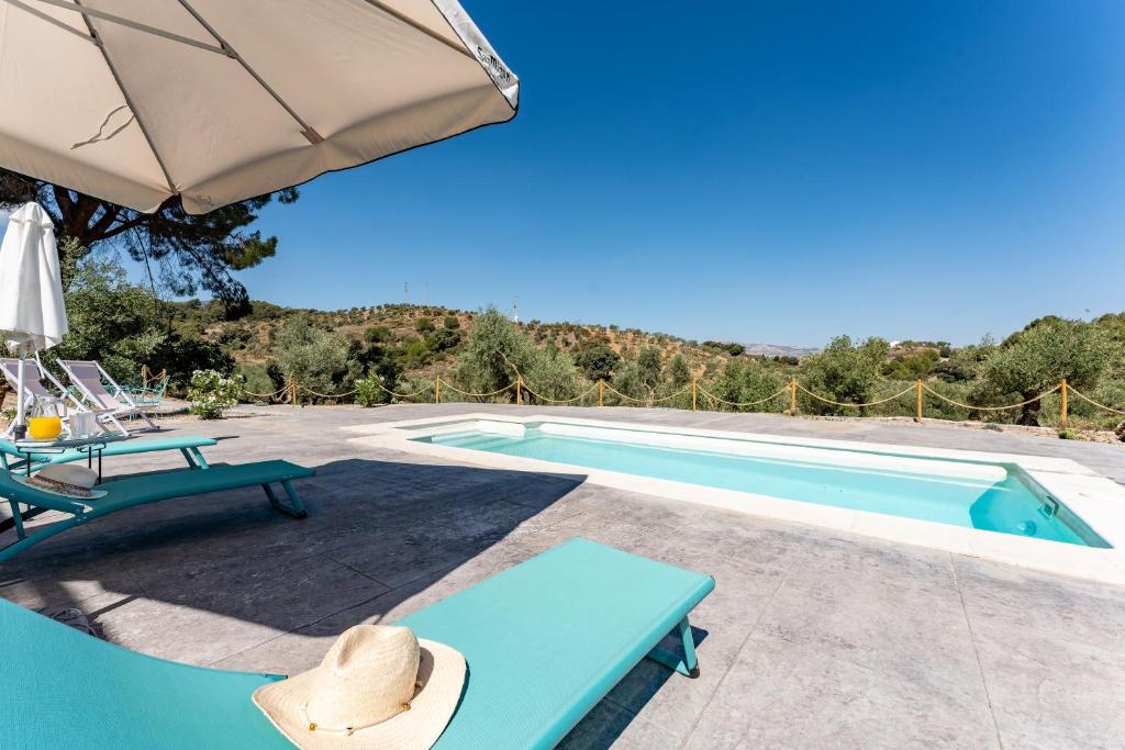 a pool with a table and chairs and an umbrella at Cortijo La Zahurdilla in Yunquera