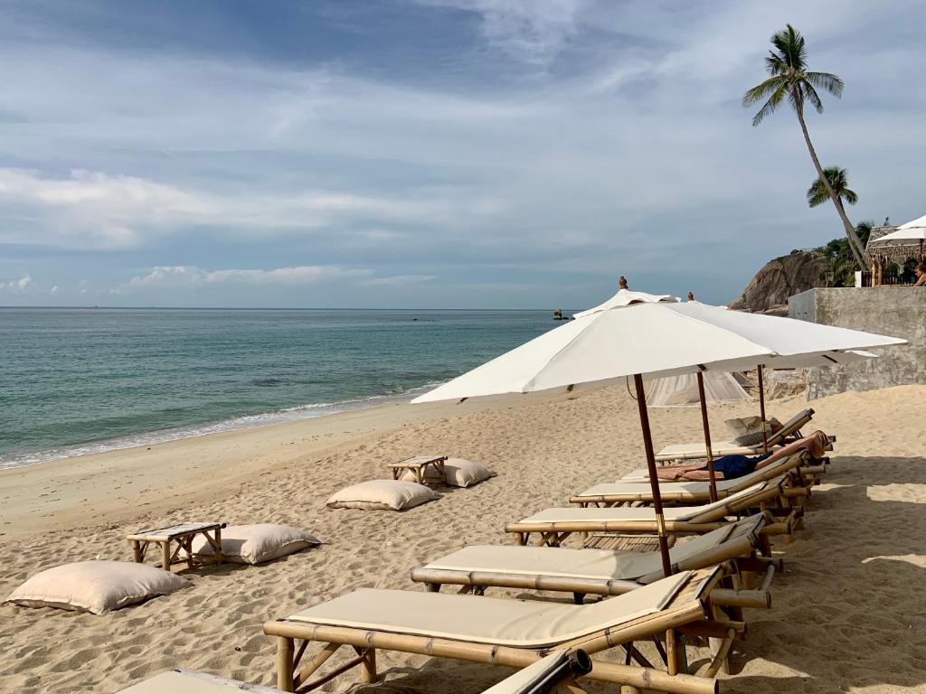 a group of lounge chairs and an umbrella on a beach at 4U Resort Samui in Lamai