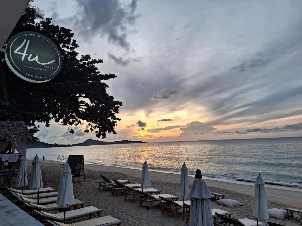 a beach with chairs and umbrellas and the ocean at 4U Resort Samui in Lamai