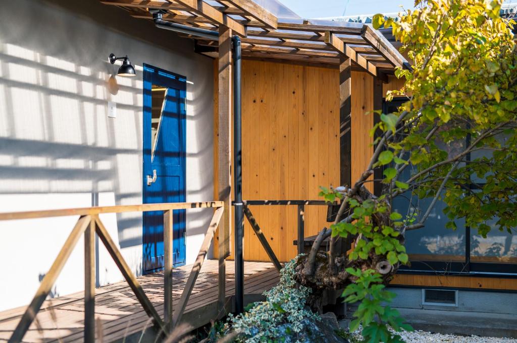una entrada de madera a una casa con puerta azul en 深々 books&stay シンシンブックスアンドステイ, en Matsukawa
