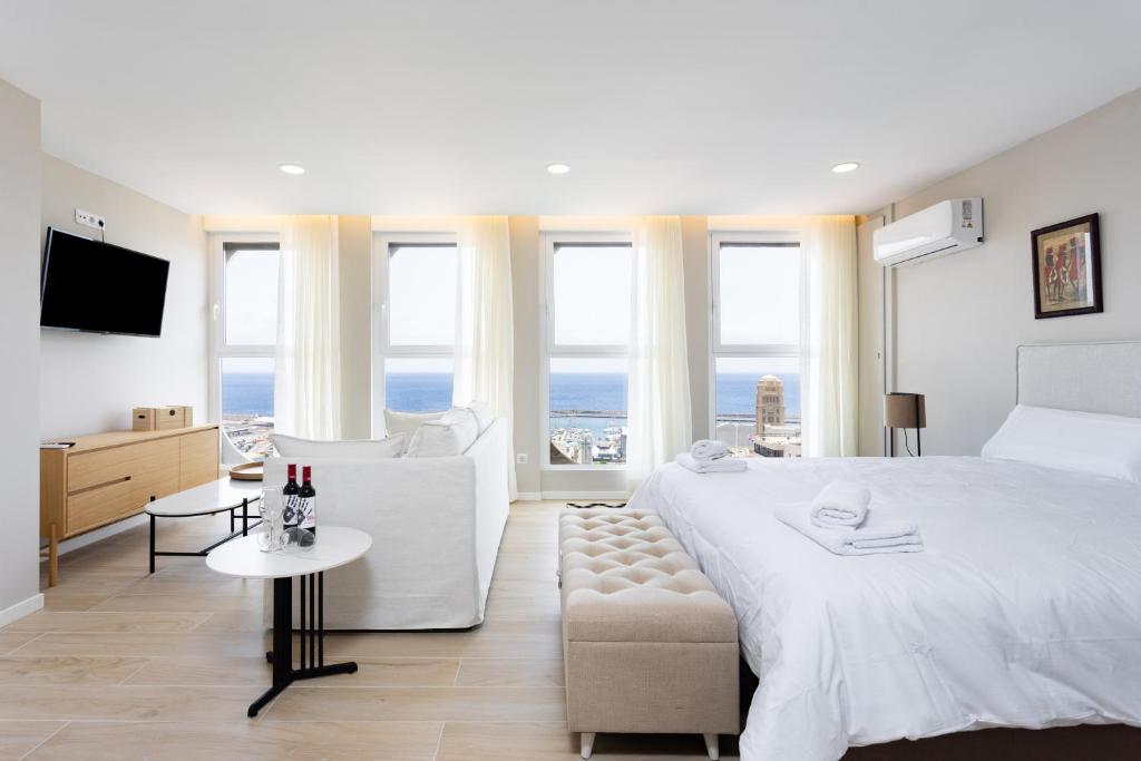 a white bedroom with a large bed and a couch at Home2Book Stylish Sea Views Studio Santa Cruz in Santa Cruz de Tenerife