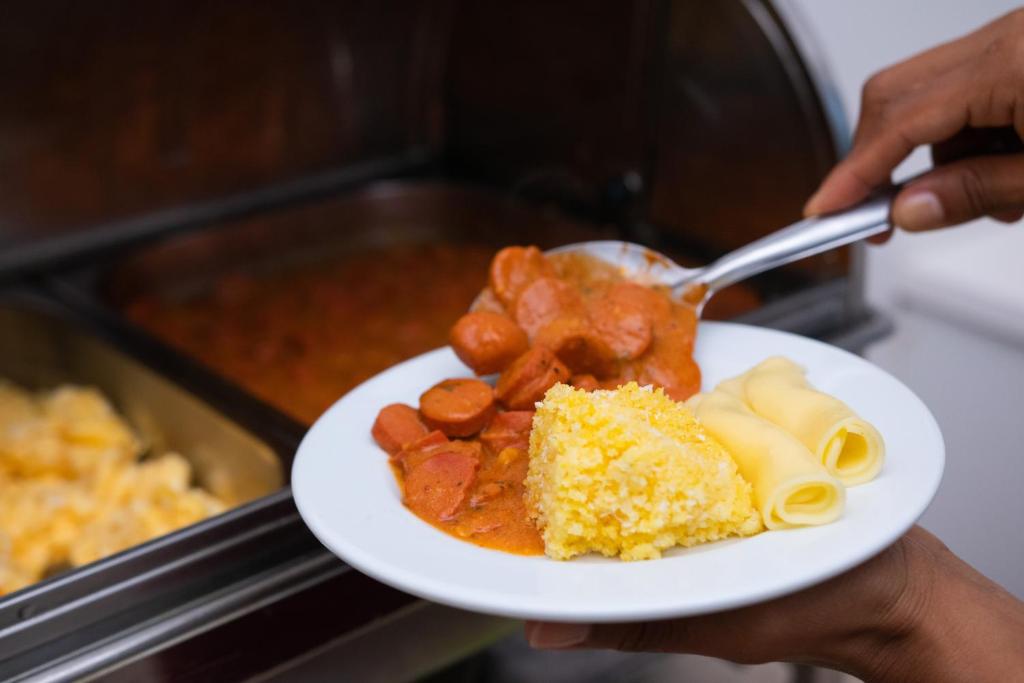 una persona sosteniendo un plato de comida con un plato de comida en Guajará Palace Hotel en Porto Velho