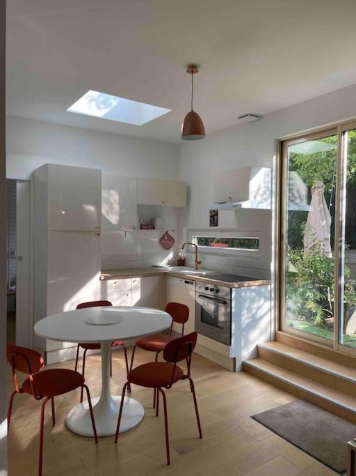 une cuisine blanche avec une table et des chaises dans l'établissement Très bel appartement avec jardin reposant, à Angers
