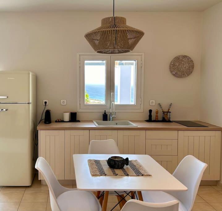 uma cozinha com uma mesa e cadeiras brancas e um frigorífico em Pytilia em Agiassos