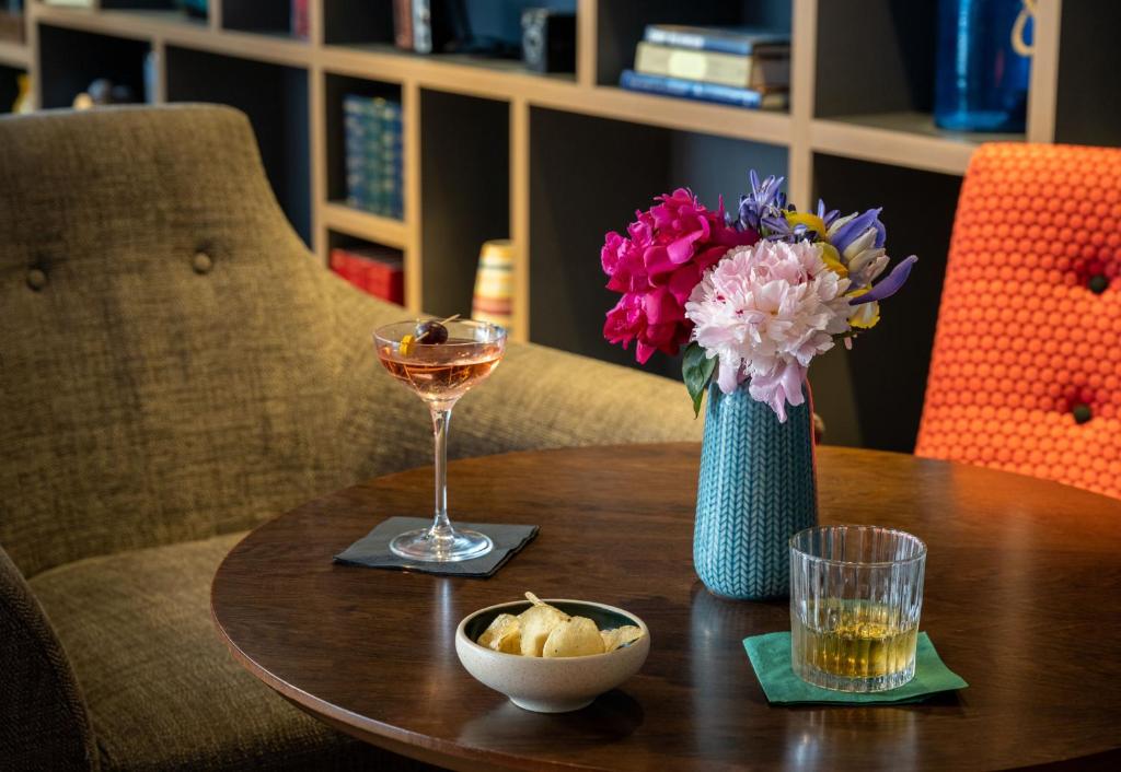 a table with a vase of flowers and a glass of wine at Leonardo Royal Hotel Brighton Waterfront in Brighton & Hove