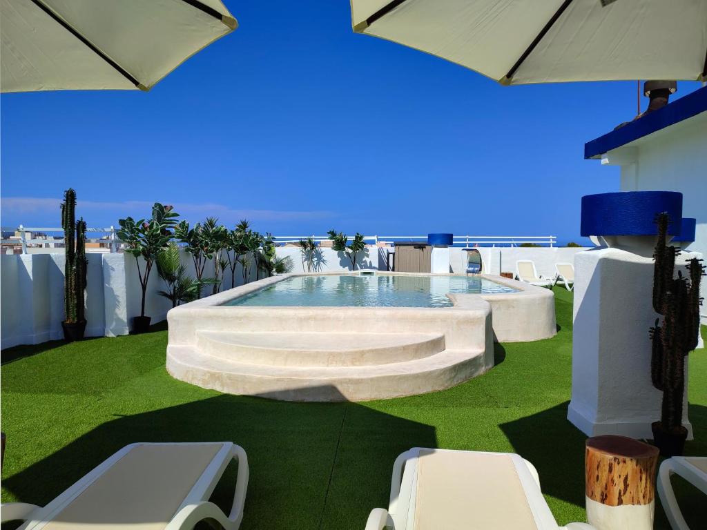 a pool on the roof of a building with chairs and umbrellas at Hotel Porto in Gandía