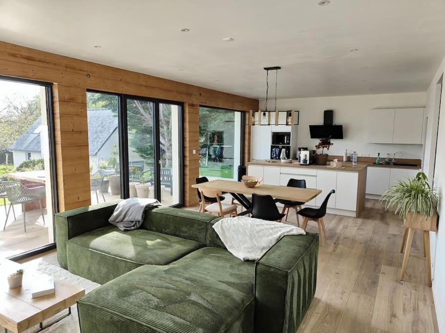 uma sala de estar com um sofá verde e uma mesa em Maison neuve proche du centre em Pabu