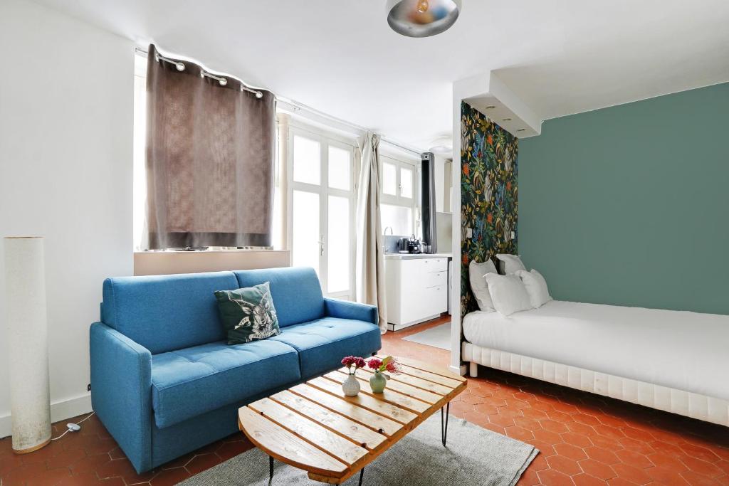 - un salon avec un canapé bleu et un lit dans l'établissement Pick A Flat's Apartment in Montorgueil - Rue Léopold Bellan, à Paris