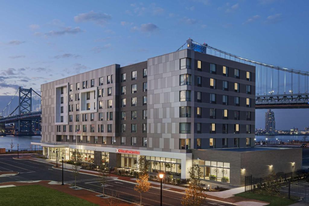 una rappresentazione di un edificio con un ponte sullo sfondo di Hilton Garden Inn Camden Waterfront Philadelphia a Camden