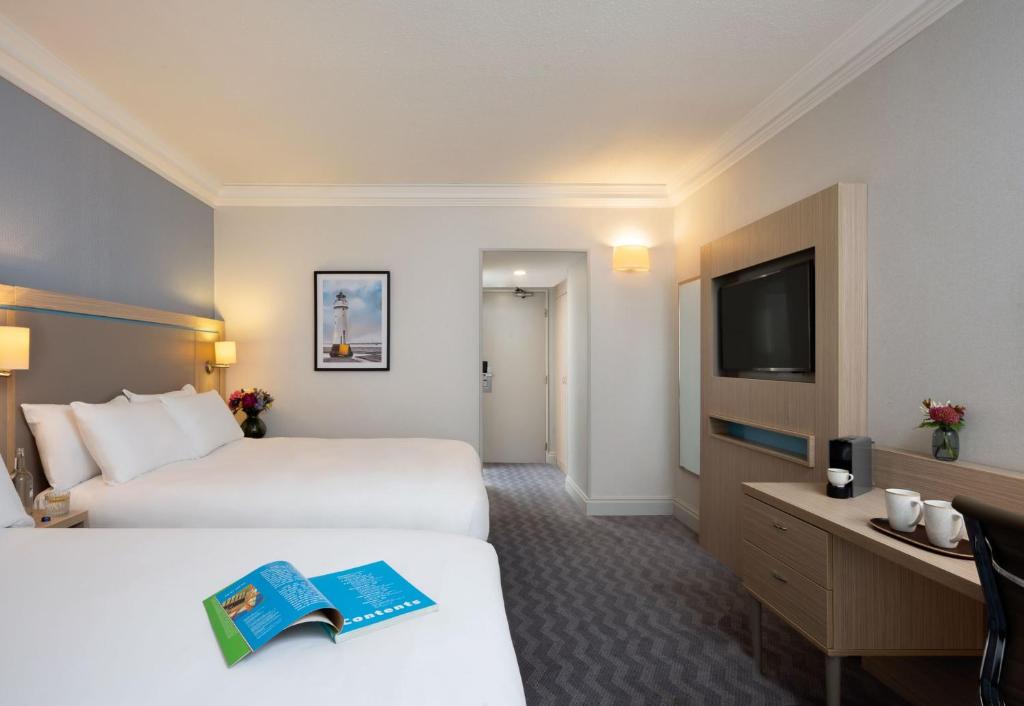 a hotel room with two beds and a tv at Leonardo Royal Hotel Brighton Waterfront in Brighton & Hove