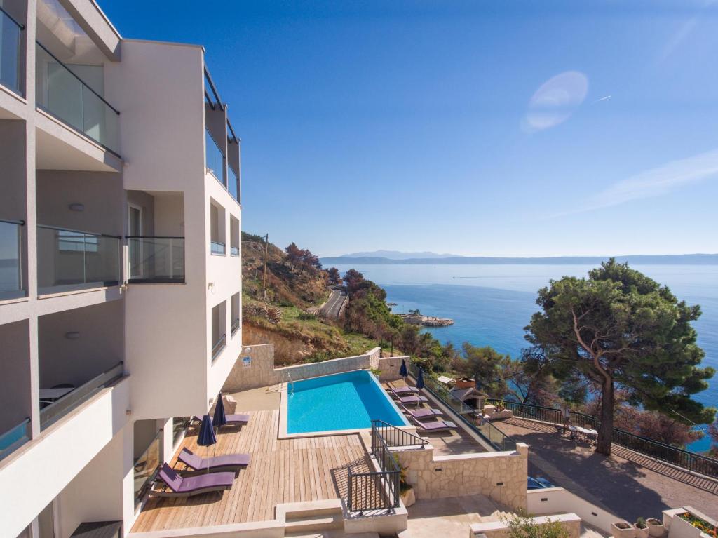 a view of a building with a swimming pool and the ocean at Villa Cascada in Podgora