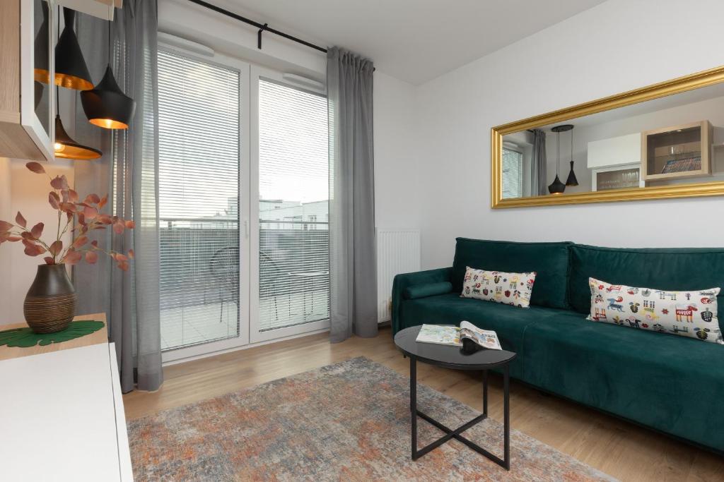 a living room with a green couch and a window at Trendy Warsaw Apartment with 2 Bedrooms, Balcony & Parking by Renters in Warsaw