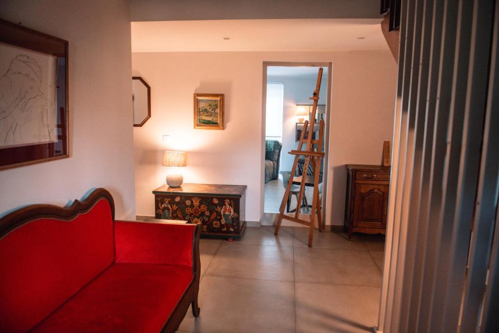 a living room with a red couch and a table at La Maison du cèdre in Dossenheim-sur-Zinsel