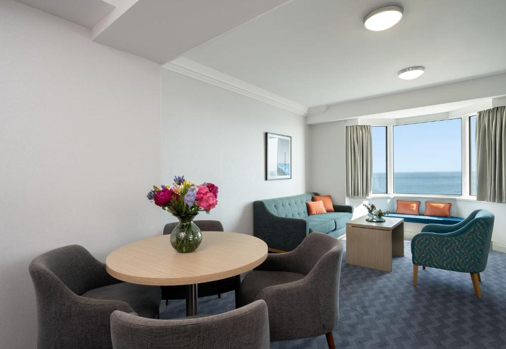 a living room with a table and chairs and a couch at Leonardo Royal Hotel Brighton Waterfront in Brighton & Hove
