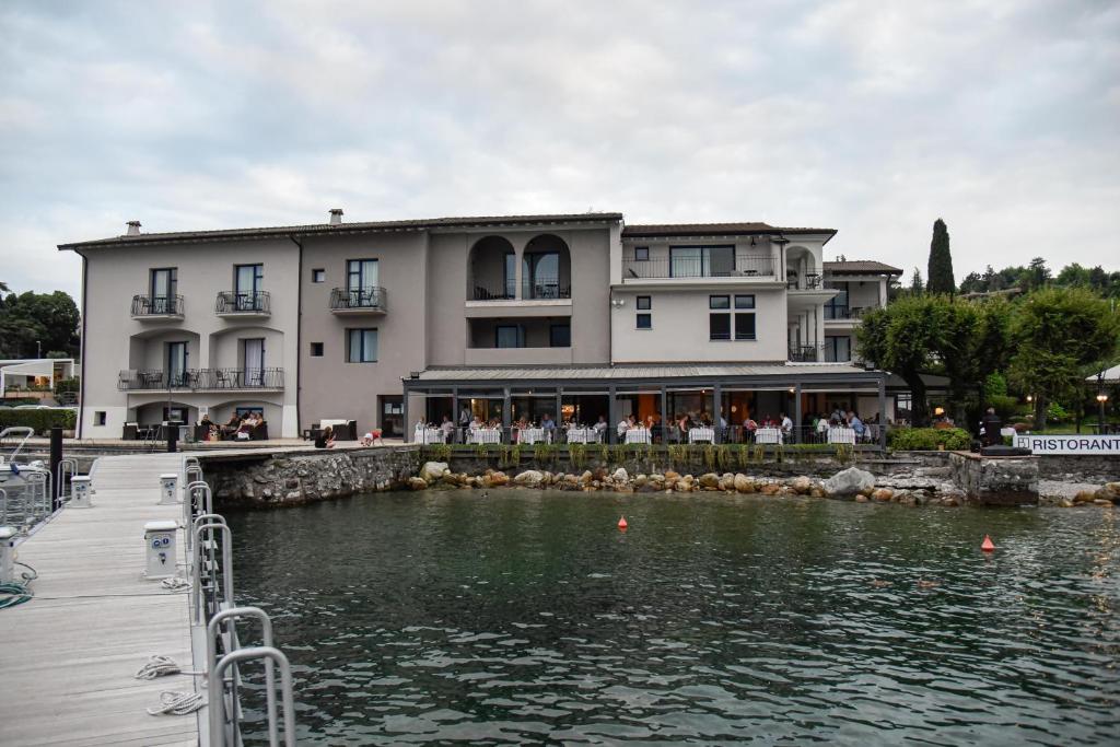 een groot gebouw naast een waterlichaam bij Bella Hotel & Restaurant with private dock for mooring boats in San Felice del Benaco