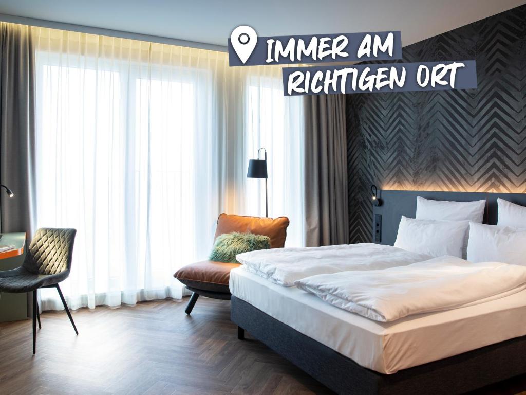 ベルリンにあるLOGINN Hotel Berlin Airportのベッドと椅子付きのホテルルーム