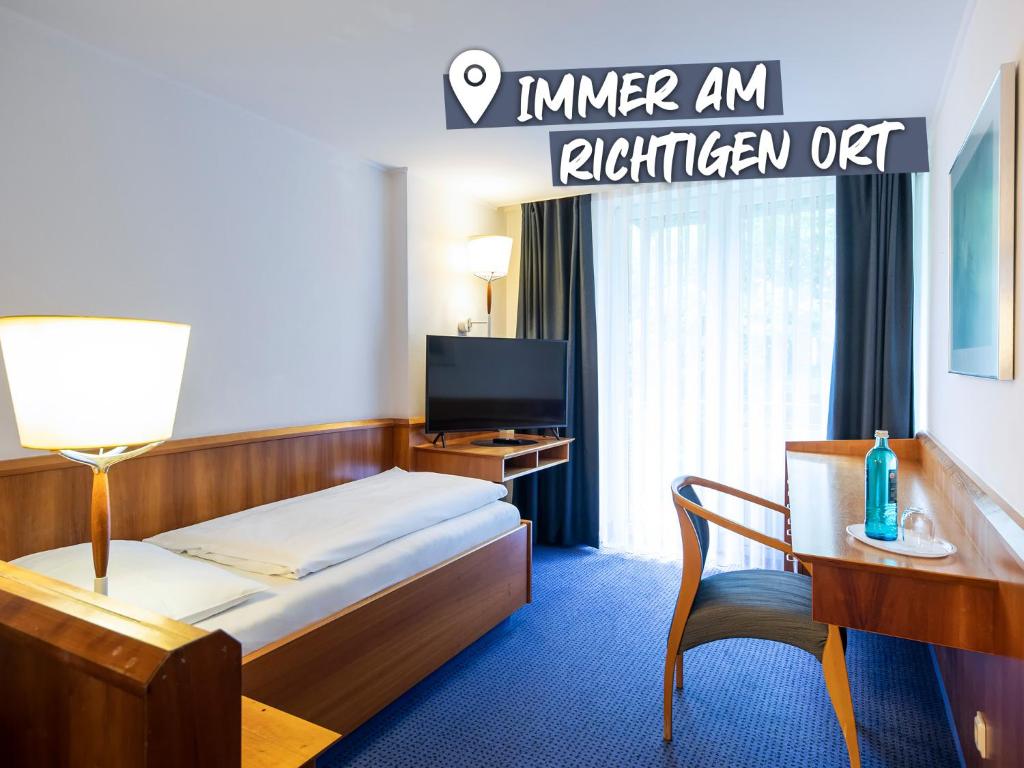 瓦爾德基興的住宿－ACHAT Hotel Karoli Waldkirchen，酒店客房配有一张床、一张书桌和一台电视。