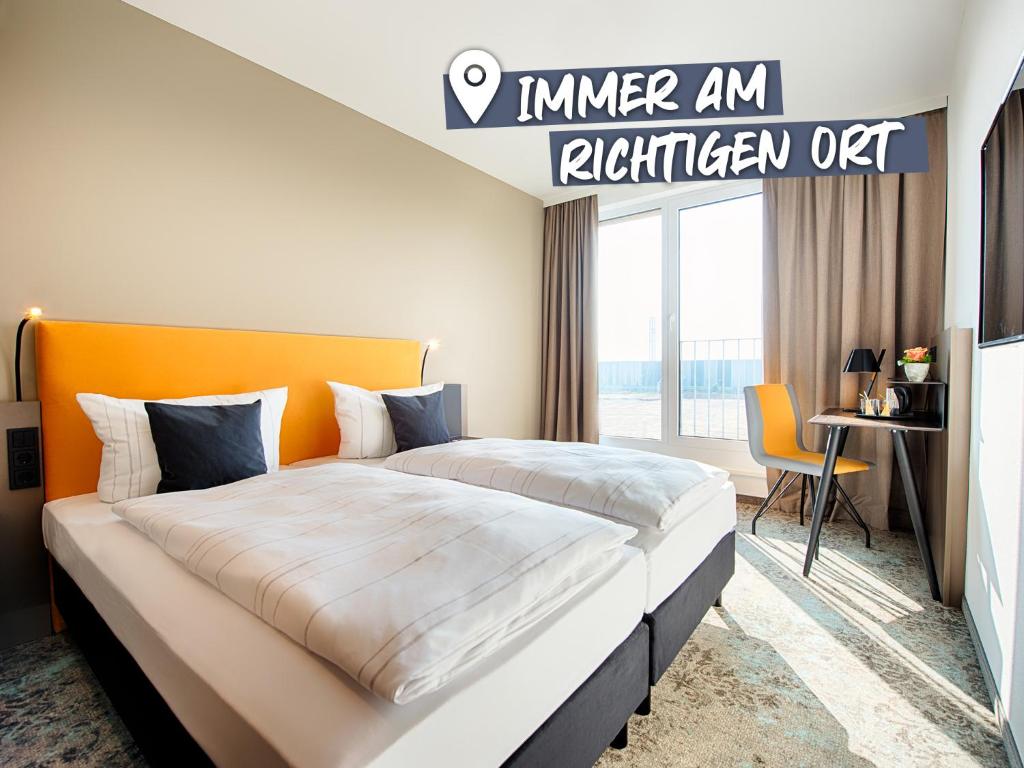 - une chambre avec un grand lit et une tête de lit orange dans l'établissement LOGINN Hotel Leipzig, à Leipzig