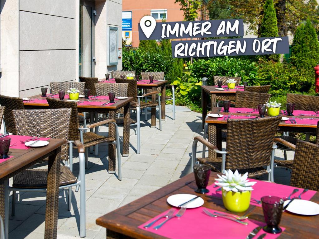 um restaurante ao ar livre com mesas e cadeiras com guardanapos cor-de-rosa em ACHAT Hotel Budapest em Budapeste