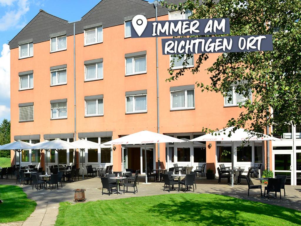 ホーデンハーゲンにあるACHAT Hotel Lüneburger Heideの建物の前にテーブルと椅子があるホテル