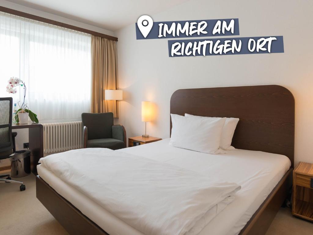 ein Hotelzimmer mit einem Bett und einem Stuhl in der Unterkunft ACHAT Hotel Corbin München Airport in Freising