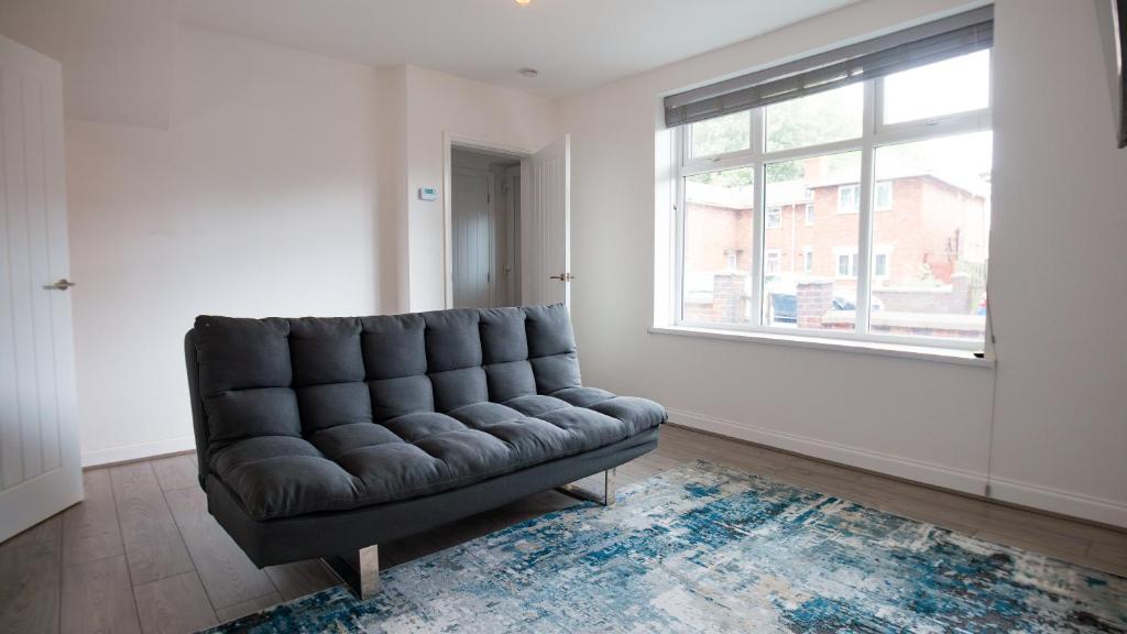 a leather couch in a living room with a window at JOIVY Charming 3-bed house in Walsall in Bescot