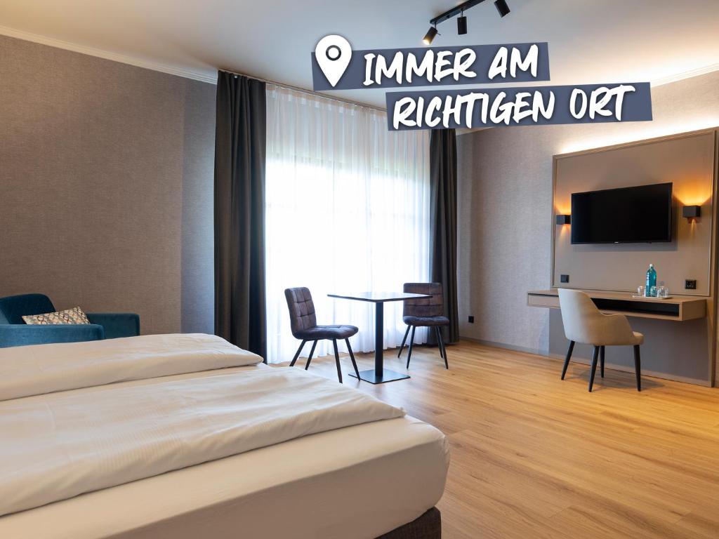 a hotel room with a bed and a table and chairs at ACHAT Hotel Waldkirchen in Waldkirchen