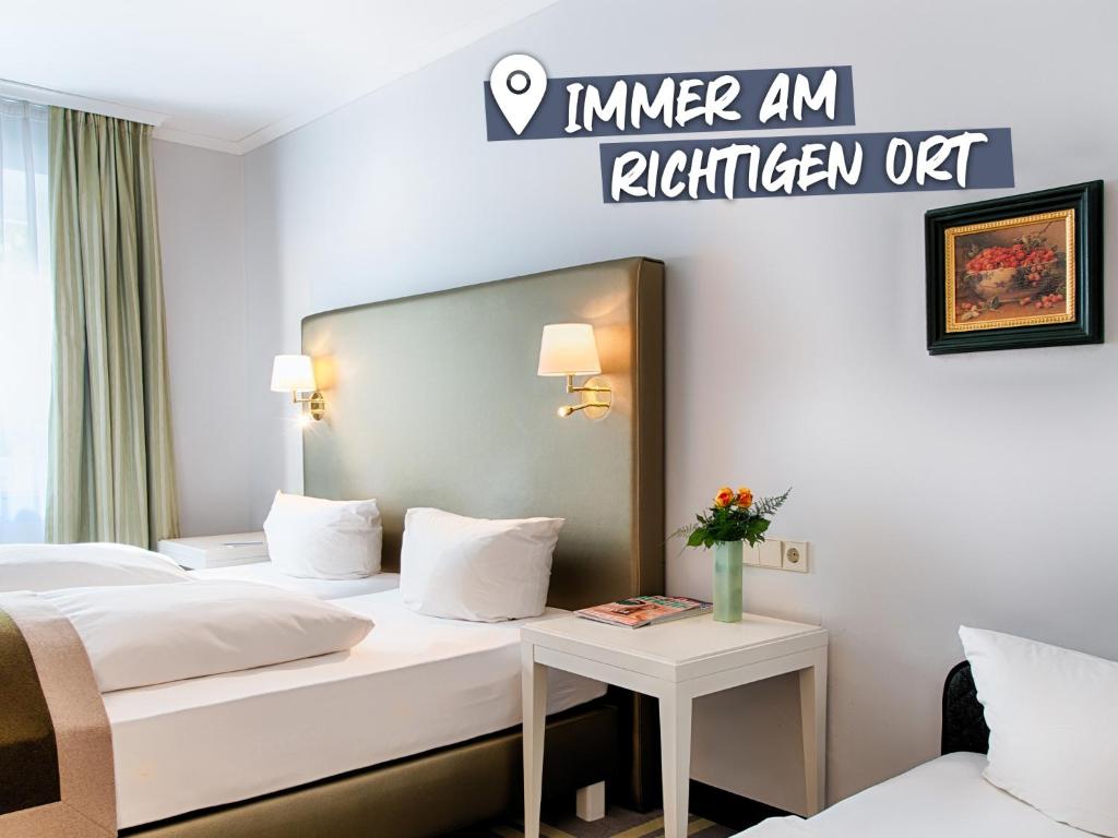 アッシュハイムにあるACHAT Hotel SchreiberHof Aschheimのベッド2台付きの客室とキッチンを読み取るサインが備わります。
