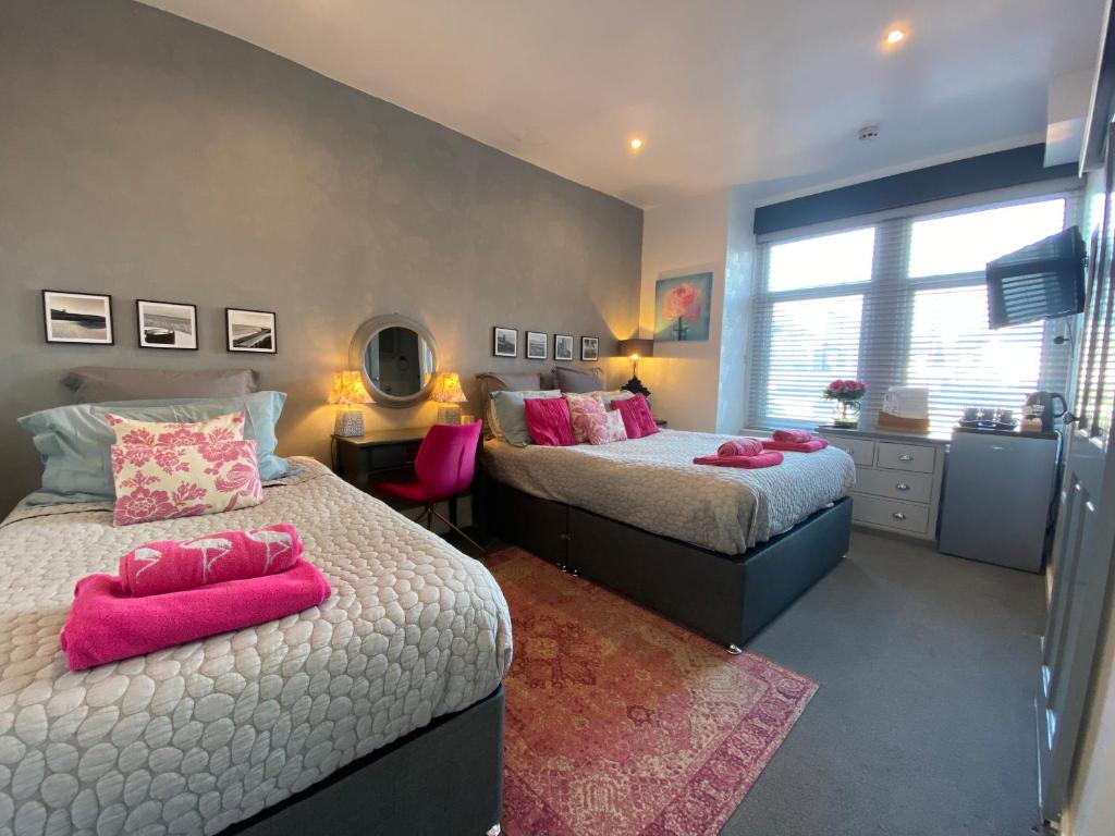 a bedroom with two beds with pink pillows at The Mayfield Boutique Guest House in Blackpool