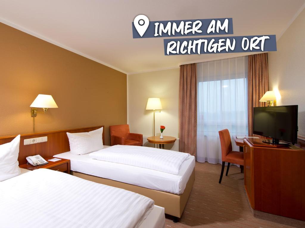 a hotel room with two beds and a television at ACHAT Hotel Schwarzheide Lausitz in Schwarzheide