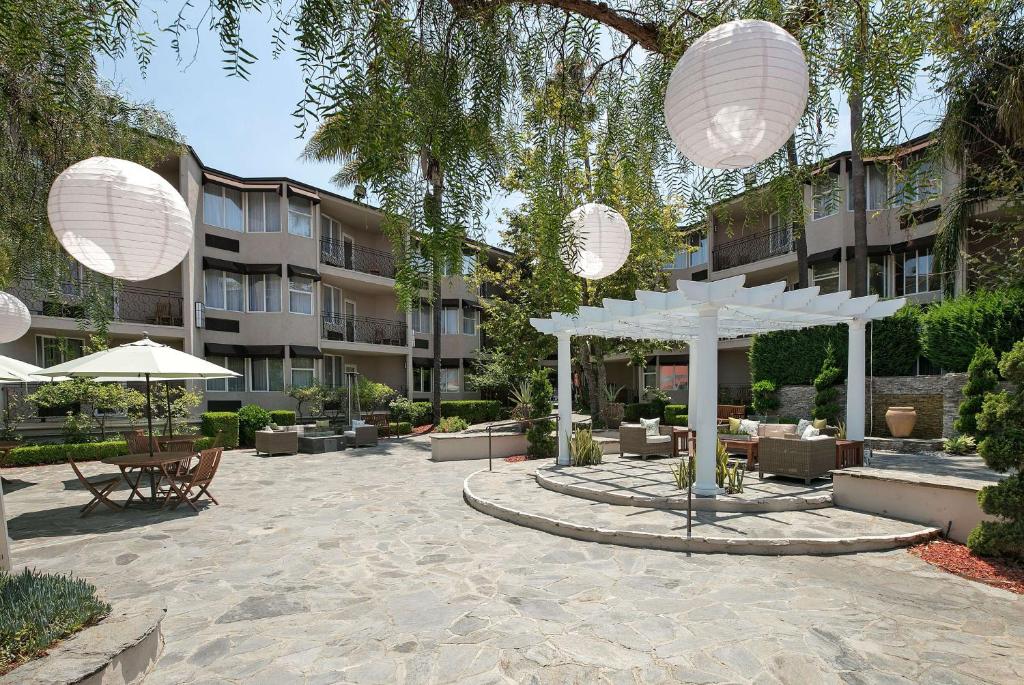 un patio con sillas y sombrillas frente a un edificio en The Belamar Hotel Manhattan Beach, Tapestry by Hilton, en Manhattan Beach